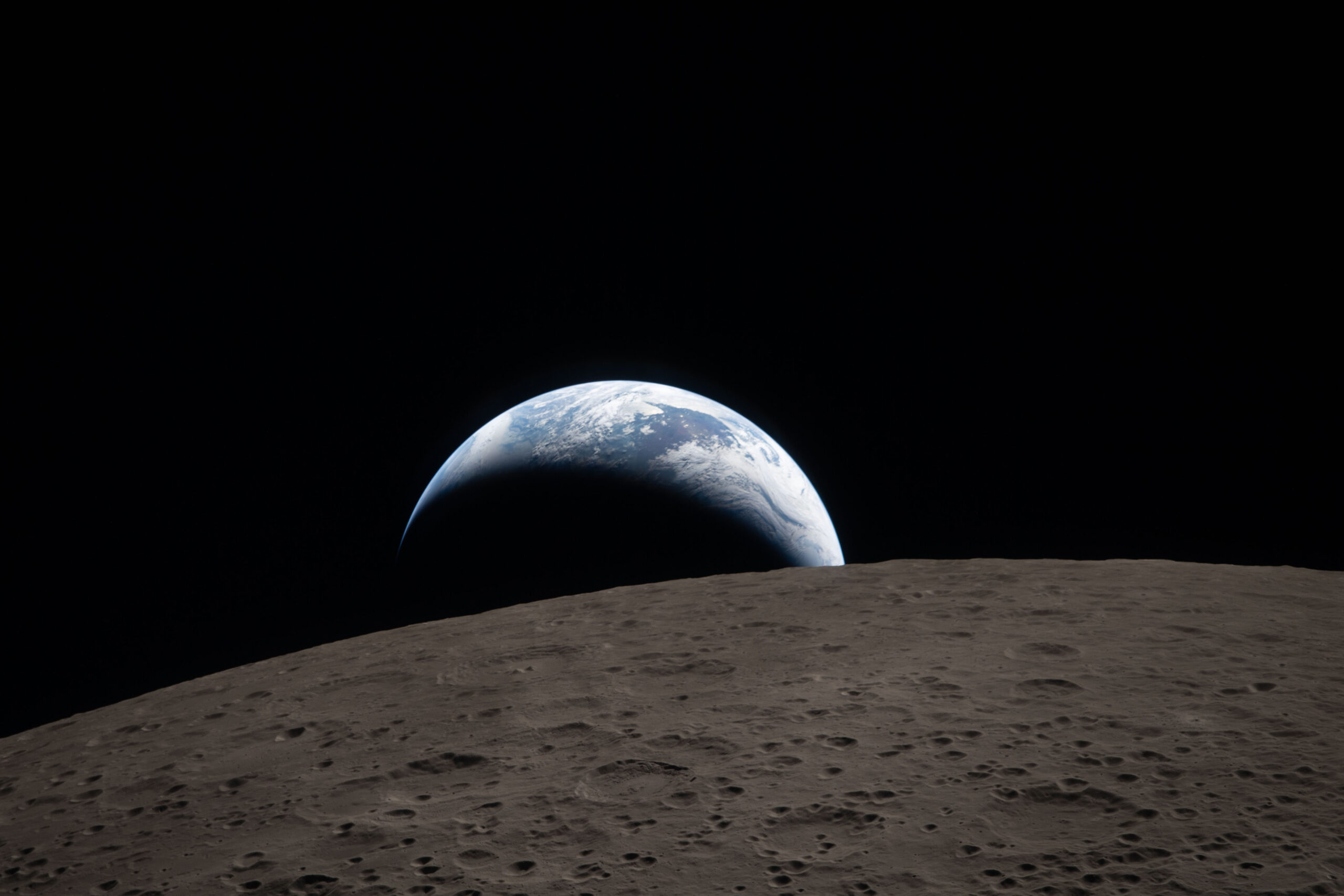 art002e009288 (April 6, 2026) – Earthset captured through the Orion spacecraft window at 6:41 p.m. EDT, April 6, 2026, during the Artemis II crew’s flyby of the Moon. A muted blue Earth with bright white clouds sets behind the cratered lunar surface. The dark portion of Earth is experiencing nighttime. On Earth’s day side, swirling clouds are visible over the Australia and Oceania region. In the foreground, Ohm crater has terraced edges and a flat floor interrupted by central peaks. Central peaks form in complex craters when the lunar surface, liquefied on impact, splashes upwards during the crater’s formation.