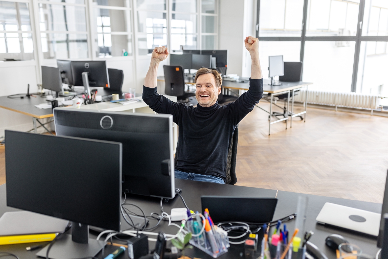 Joyful businessman celebrating success at workplace in office