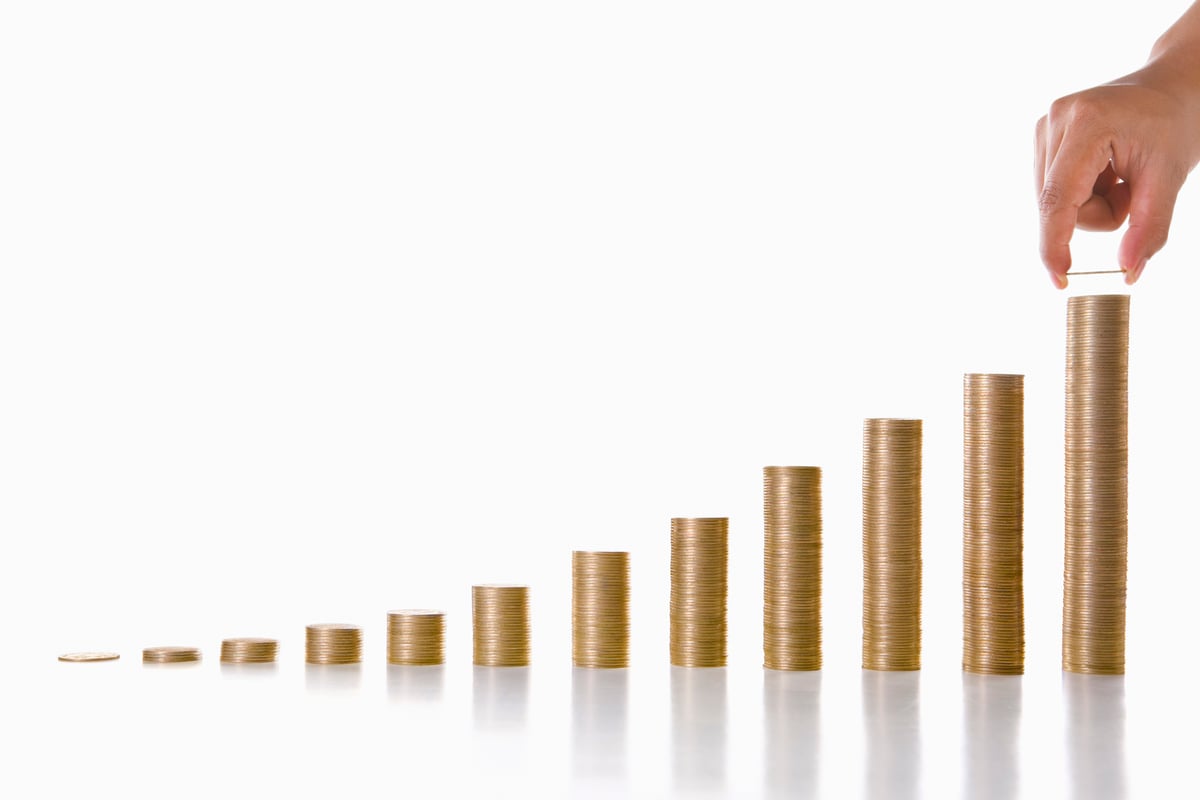A stack of gold coins is rising in the shape of a bar chart.